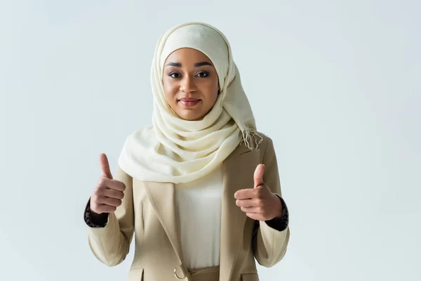 Happy muslim woman in hijab showing thumbs up and smiling isolated on grey — Stock Photo