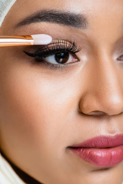 Primer plano de la mujer musulmana aplicando sombra de ojos con cepillo cosmético - foto de stock