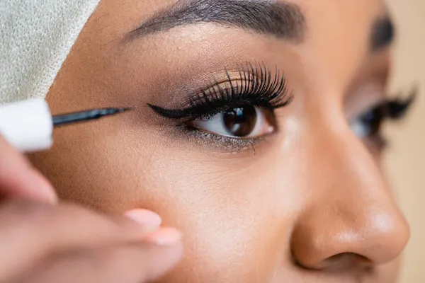 Close-up de jovem mulher árabe aplicando forro olho preto — Fotografia de Stock