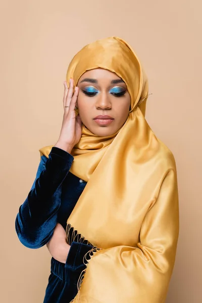 Femme musulmane en hijab avec fard à paupières lumineux isolé sur beige — Photo de stock