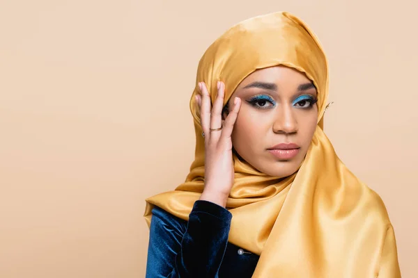 Femme musulmane en hijab avec un maquillage lumineux en regardant la caméra isolée sur beige — Photo de stock