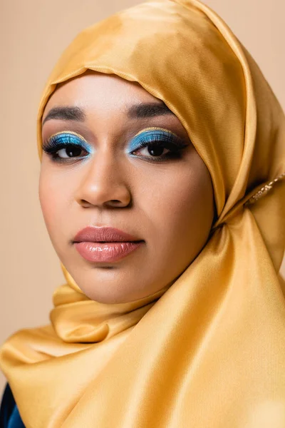Pretty muslim woman in yellow hijab with bright makeup isolated on beige — Stock Photo
