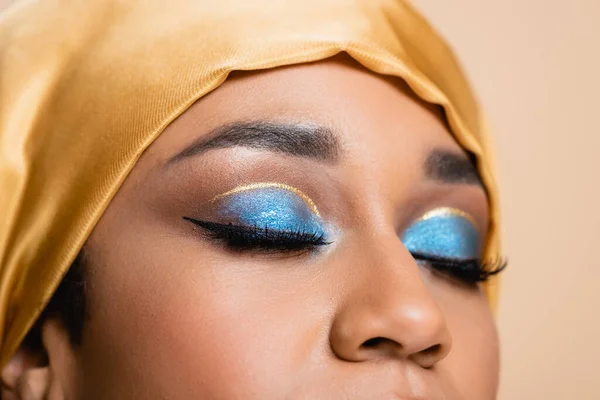 Vista recortada de la mujer musulmana en hijab con maquillaje de ojos brillantes aislados en beige - foto de stock