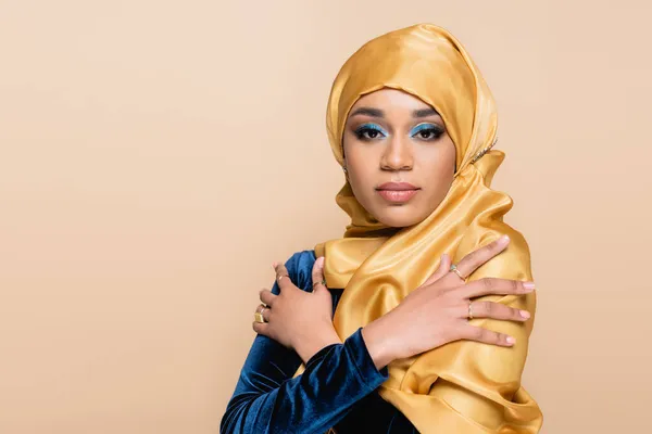 Junge muslimische Frau im gelben Hijab posiert mit verschränkten Armen isoliert auf beige — Stockfoto