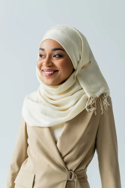 Гарна мусульманка в білому хіджабі, дивлячись далеко, посміхаючись ізольовано на сірому — стокове фото