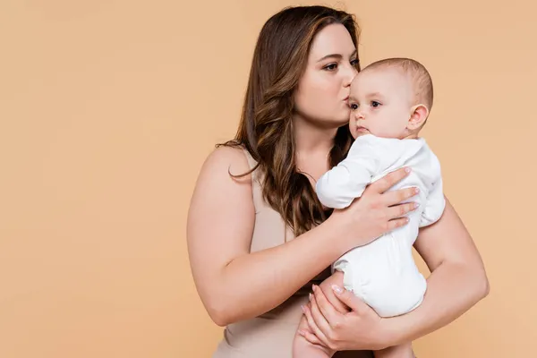 Além de tamanho mãe beijando bebê filha isolada no bege — Fotografia de Stock