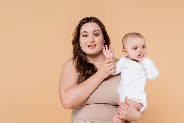 Sonriente más tamaño padre de la mano de la hija del bebé aislado en beige - foto de stock