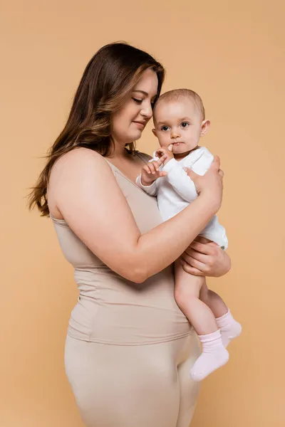 Jovem plus size mulher abraçando filha isolada no bege — Fotografia de Stock