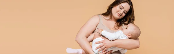 Happy plus size mother looking at daughter isolated on beige, banner — Stock Photo