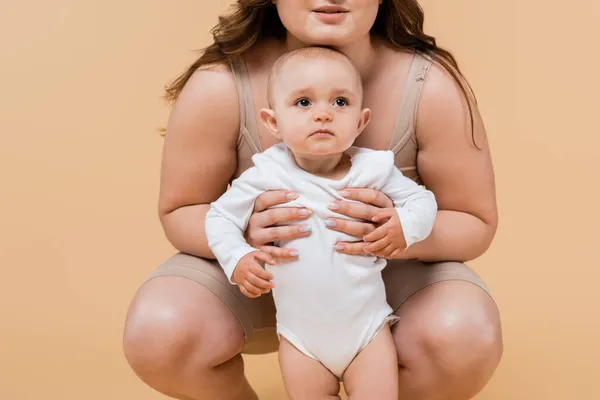 Body positive woman hugging baby daughter isolated on beige — Stock Photo