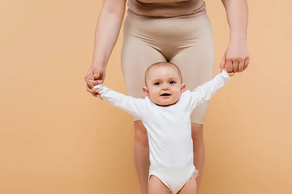 Body positive woman holding hands of child isolated on beige — Stock Photo