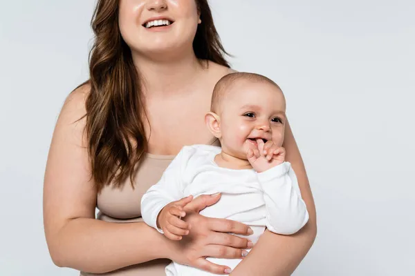 Fröhliche Plus-Size-Frau hält fröhliches Baby isoliert auf grau — Stockfoto