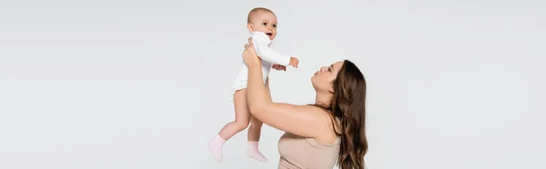 Jolie mère taille plus levant bébé fille isolé sur gris, bannière — Photo de stock
