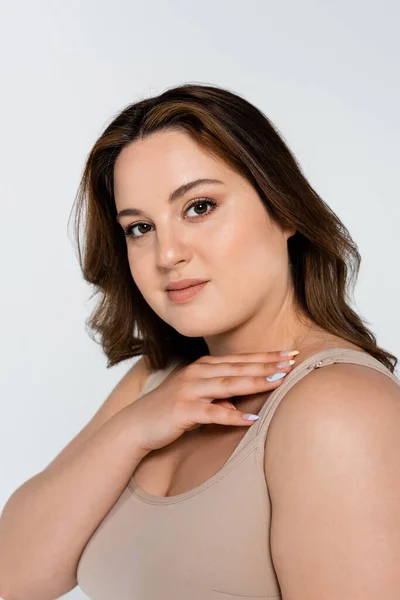 Portrait of young brunette plus size woman looking at camera isolated on grey — Stock Photo