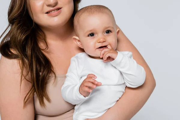 Plus tamaño madre sosteniendo positivo bebé niña aislado en gris - foto de stock