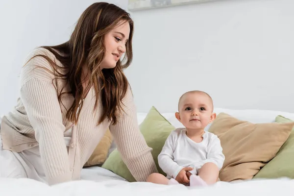 Lächelnde Mutter mit Übergewicht schaut Baby-Mädchen im Bett an — Stockfoto
