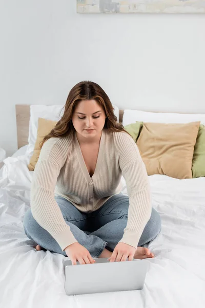 Body positive freelancer using laptop on bed at home — Stock Photo