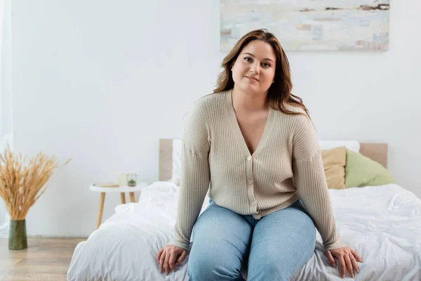 Smiling woman with overweight sitting on bed at home — Stock Photo