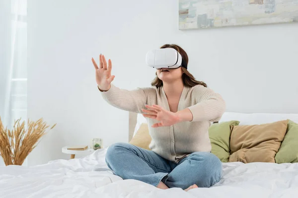 Femme de taille plus en utilisant casque de réalité virtuelle sur le lit — Photo de stock