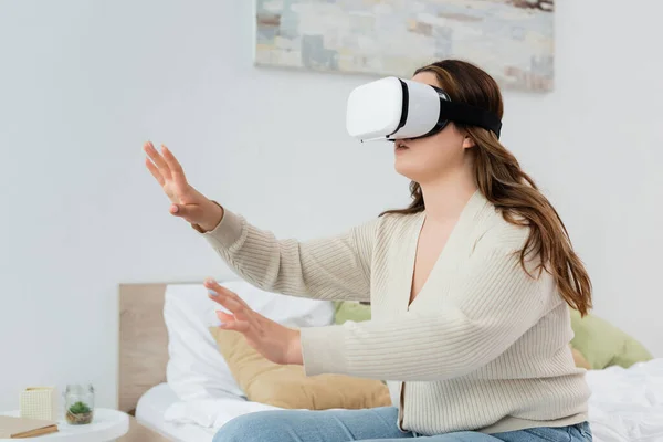 Brünett körper positiv frau im vr headset gaming im schlafzimmer — Stockfoto