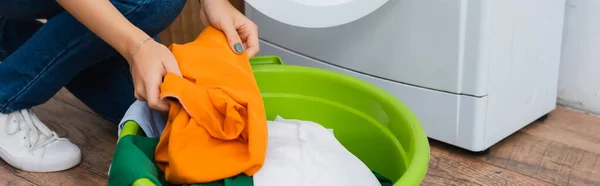 Vista parcial da mulher segurando roupas perto de lavandaria e máquina de lavar roupa, banner — Fotografia de Stock