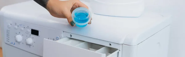 Partial view of woman holding cap with liquid detergent near washing machine, banner — Stock Photo