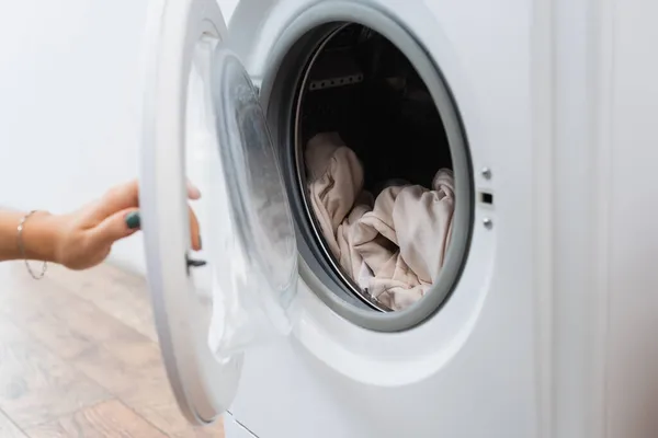 Ausgeschnittene Ansicht einer Frau, die Waschmaschine mit Wäsche öffnet — Stockfoto