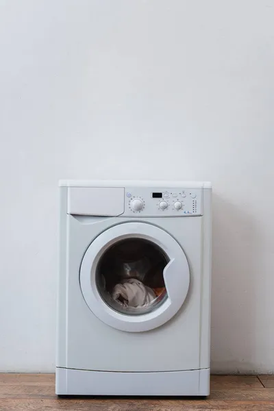 Modern washing machine with laundry near white wall — Stock Photo