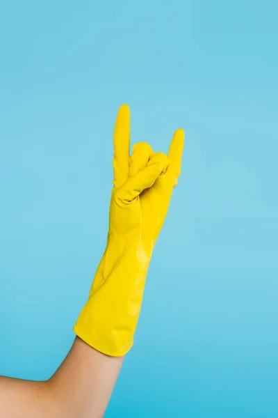 Vista ritagliata della donna in guanto di gomma giallo mostrando segno di roccia isolato su blu — Foto stock