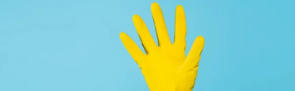 Cropped view of female hand in yellow rubber glove isolated on blue, banner — Stock Photo