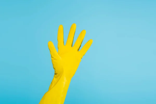 Vista parcial de la mujer con guante de goma amarillo aislado en azul - foto de stock