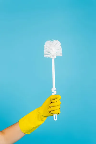 Vue partielle de la femme au foyer en gant de caoutchouc jaune tenant la brosse de toilette isolée sur bleu — Photo de stock