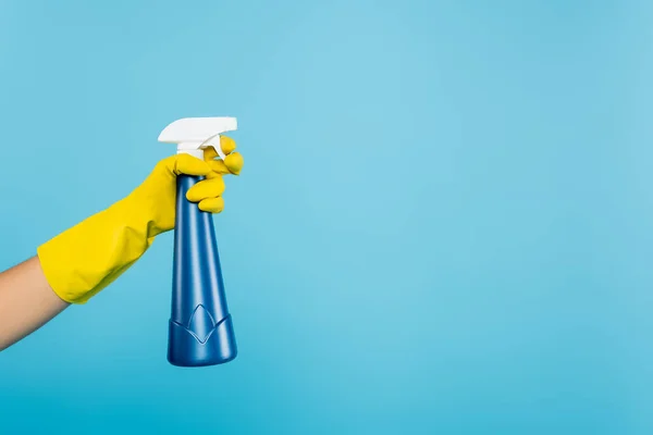 Vista parcial de la mujer en guante de goma amarillo que sostiene la botella de aerosol con detergente aislado en azul - foto de stock