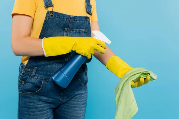 Abgeschnittene Ansicht der Hausfrau, die Reinigungsmittel auf Lappen sprüht, isoliert auf Blau — Stockfoto