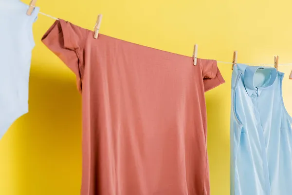 Clean laundry hanging on rope on yellow background — Stock Photo