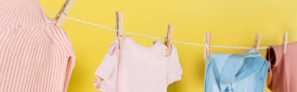Close up view of blurred clothes hanging on rope on yellow background, banner — Stock Photo