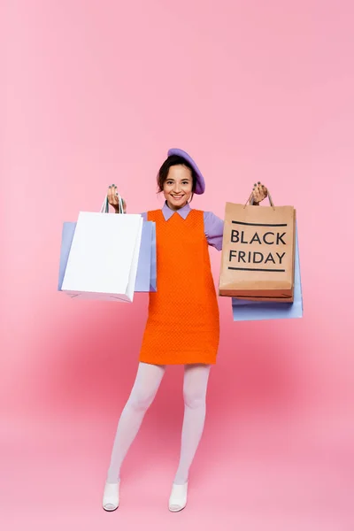 Donna felice che tiene acquisti e shopping bag con scritta nera venerdì su rosa — Foto stock