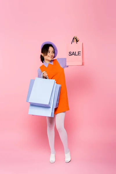 Femme élégante tenant achats et sac à provisions avec lettrage de vente sur rose — Photo de stock