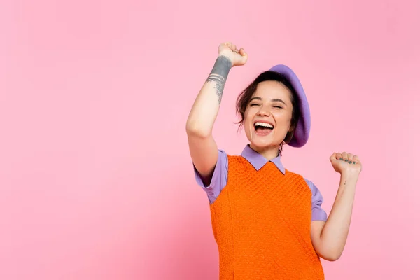 Aufgeregte tätowierte Frau zeigt Jubelgeste und schreit vereinzelt auf rosa — Stockfoto