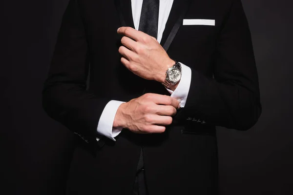 Cropped view of elegant man in suit buttoning sleeve of white shirt isolated on black — Stock Photo