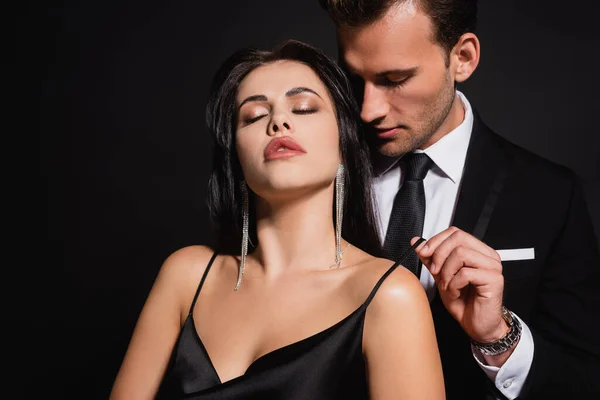 Stilvoller Mann verführt sinnliche und stilvolle Frau steht mit geschlossenen Augen isoliert auf schwarz — Stockfoto