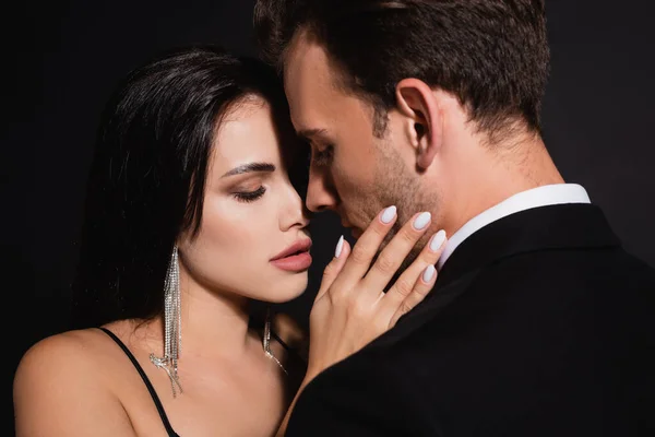 Young elegant couple standing face to face isolated on black — Stock Photo