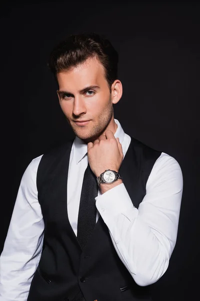 Young elegant man in white shirt and vest looking at camera isolated on black — Stock Photo