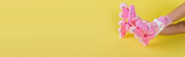 Vista recortada de la mujer joven afroamericana es patines de rodillo de color rosa en amarillo, bandera - foto de stock