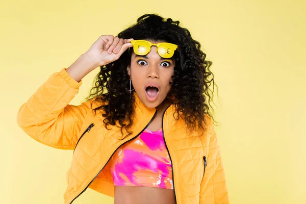 Sorprendió a la joven afroamericana ajustando gafas de sol con letras de venta aisladas en amarillo - foto de stock