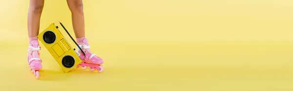Обрізаний вид афроамериканської жінки в роликових ковзанах біля ретро бумбоксу на жовтому, банер — стокове фото