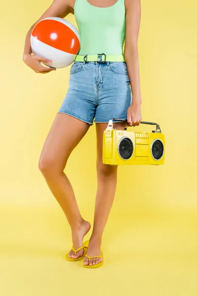 Cropped view of african american woman holding boombox and inflatable ball on yellow — Stock Photo