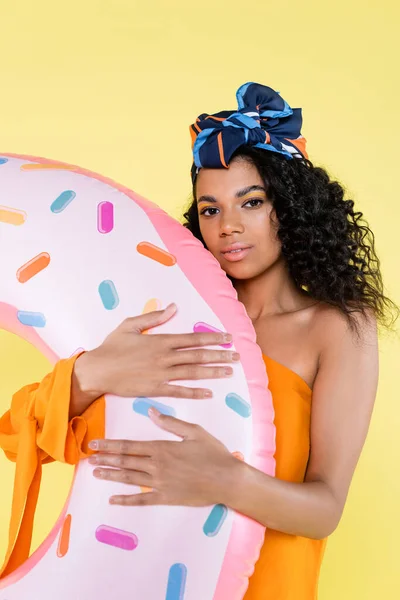 Afro-américaine en foulard tenant donut gonflable isolé sur jaune — Photo de stock