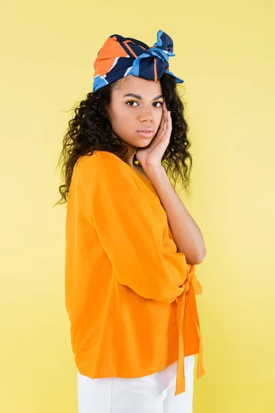 Young african american woman in headscarf posing isolated on yellow — Stock Photo