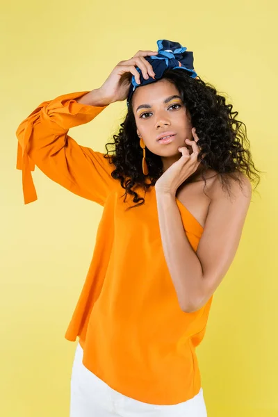 Encaracolado afro-americano mulher em kerchief posando enquanto olha para câmera isolada no amarelo — Fotografia de Stock